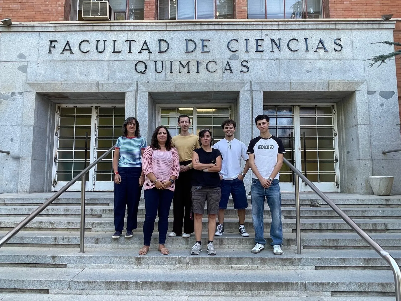 Six researchers pose on the steps of the Faculty of Chemistry at the Complutense University of Madrid