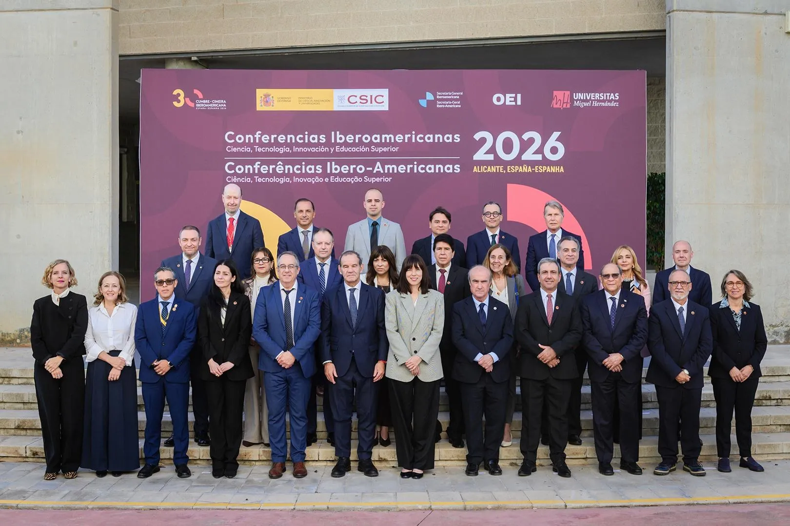 Group photo of around thirty ministers and officials standing on steps in front of a maroon backdrop for the 2026 Ibero-American Conferences in Alicante