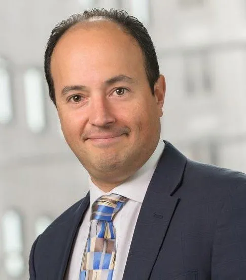 Portrait of a man in a dark suit and a blue checked tie
